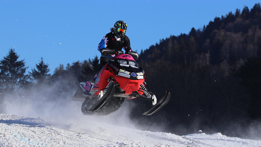 Snowmobiler Riding Through A Snowy Trail In Temiskaming Shores Ontario White The Rider Is Catching Air And Is Surrounded By Beautiful Winter Scenery And Captures The Excitement And Thrill Of Snowmobiling In The Best Destination In Ontario